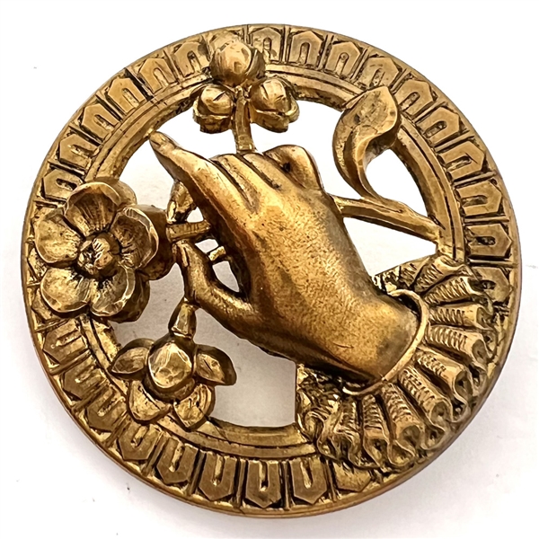Stamped brass button of hand holding flowers.