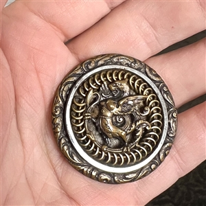 Brass button of a dragon standing.