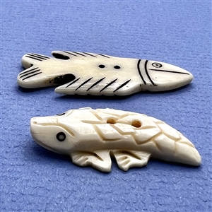 Two carved natural material buttons of a fish and a lizard.