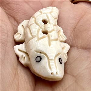 Two carved natural material buttons of a fish and a lizard.