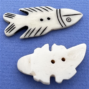 Two carved natural material buttons of a fish and a lizard.