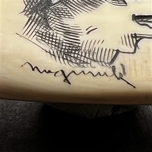 Scrimshaw button of a husky dog on natural material