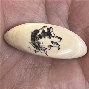 Scrimshaw button of a husky dog on natural material