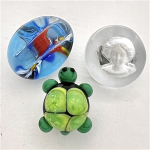 Three glass studio buttons of turtle, head etc.