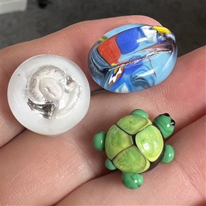 Three glass studio buttons of turtle, head etc.