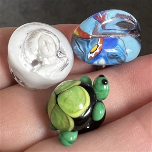 Three glass studio buttons of turtle, head etc.