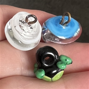 Three glass studio buttons of turtle, head etc.