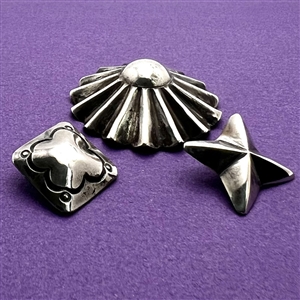 Three sculptural Native American silver buttons of assorted shapes.