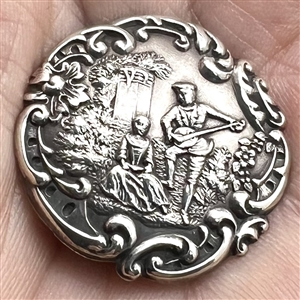 Hallmarked silver button of man serenading a woman in a garden.