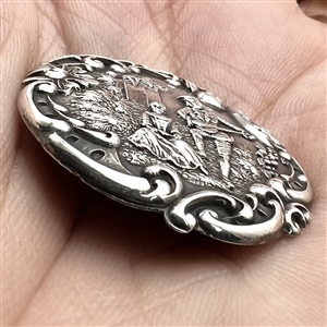 Hallmarked silver button of man serenading a woman in a garden.