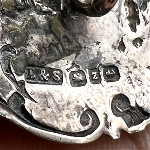 Hallmarked silver button of man serenading a woman in a garden.
