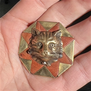 Handkerchief corner metal studio button of a cat by Phil Linley.