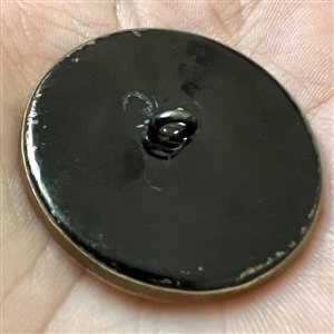 Brass button of a sprite (?) riding a dragonfly while playing an instrument.