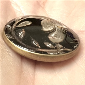 Flower and leaves reverse painted on glass over iridescent celluloid set in metal button.