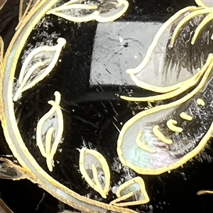 Flower and leaves reverse painted on glass over iridescent celluloid set in metal button.