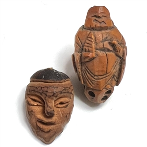 Two Folk Art carved fruit pit buttons of people.