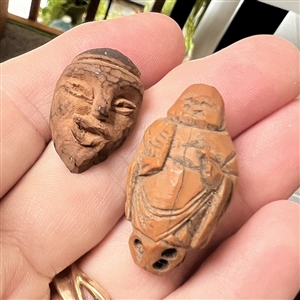 Two Folk Art carved fruit pit buttons of people.