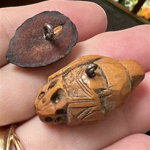Two Folk Art carved fruit pit buttons of people.