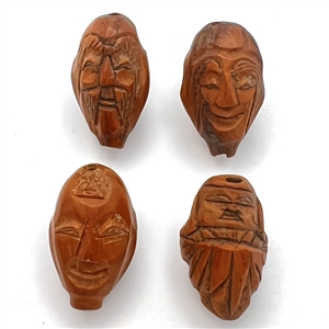 Four Folk Art carved fruit pit buttons of faces.