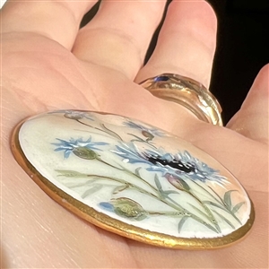 Painted porcelain button of blue cornflowers.