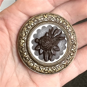 A 19th c. Button with gutta percha rose in steel collet and a detailed brass border.