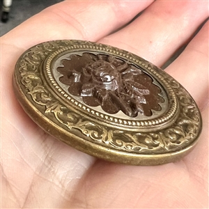 A 19th c. Button with gutta percha rose in steel collet and a detailed brass border.