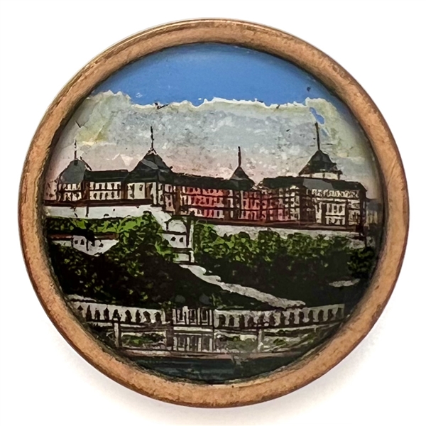 Reverse painted under glass button of an architectural scene of a large building.