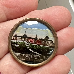 Reverse painted under glass button of an architectural scene of a large building.