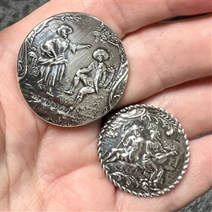 Two silver buttons of people in nature.