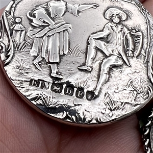 Two silver buttons of people in nature.