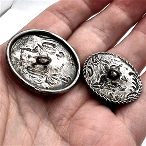 Two silver buttons of people in nature.