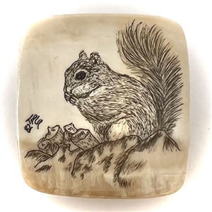 Scrimshaw natural material button of a squirrel eating.