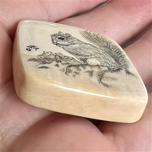 Scrimshaw natural material button of a squirrel eating.