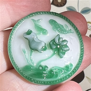 Peking glass button of two koi swimming with water plants.