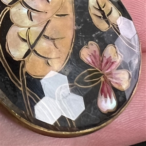 Flower and leaves reverse painted on faceted glass over iridescent celluloid set in metal button.