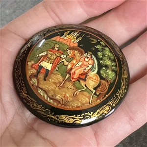 Russian lacquer button of a man leading a woman on a horse in front of a castle at night. 