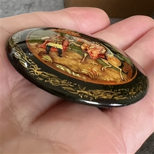 Russian lacquer button of a man leading a woman on a horse in front of a castle at night. 