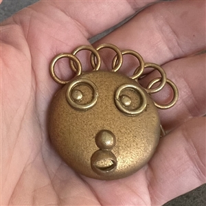 Painted celluloid goofie button of a funny face and crazy hair.