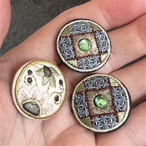 Three Edwardian fabric buttons.
