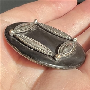 A 19th c. grey pearl button with metal design.