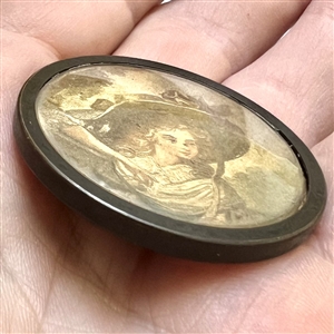 Printed fabric under glass button of a woman in a huge hat.