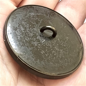 Printed fabric under glass button of a woman in a huge hat.