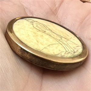 Incised and inked natural material button of a man with a waling cane.