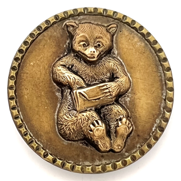 Brass button of a teddy bear with a letter. 