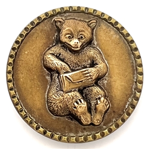 Brass button of a teddy bear with a letter. 