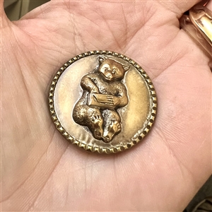 Brass button of a teddy bear with a letter. 