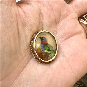 Bird button with real bird feathers over pearl under glass set in metal. 