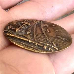 A 19th c. Brass button of fouled anchor and sea scene from ship. 