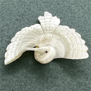 Carved pearl button of a realistic flying crane.