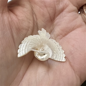 Carved pearl button of a realistic flying crane.
